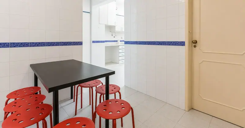 Tiled kitchen with a dining table and red stools